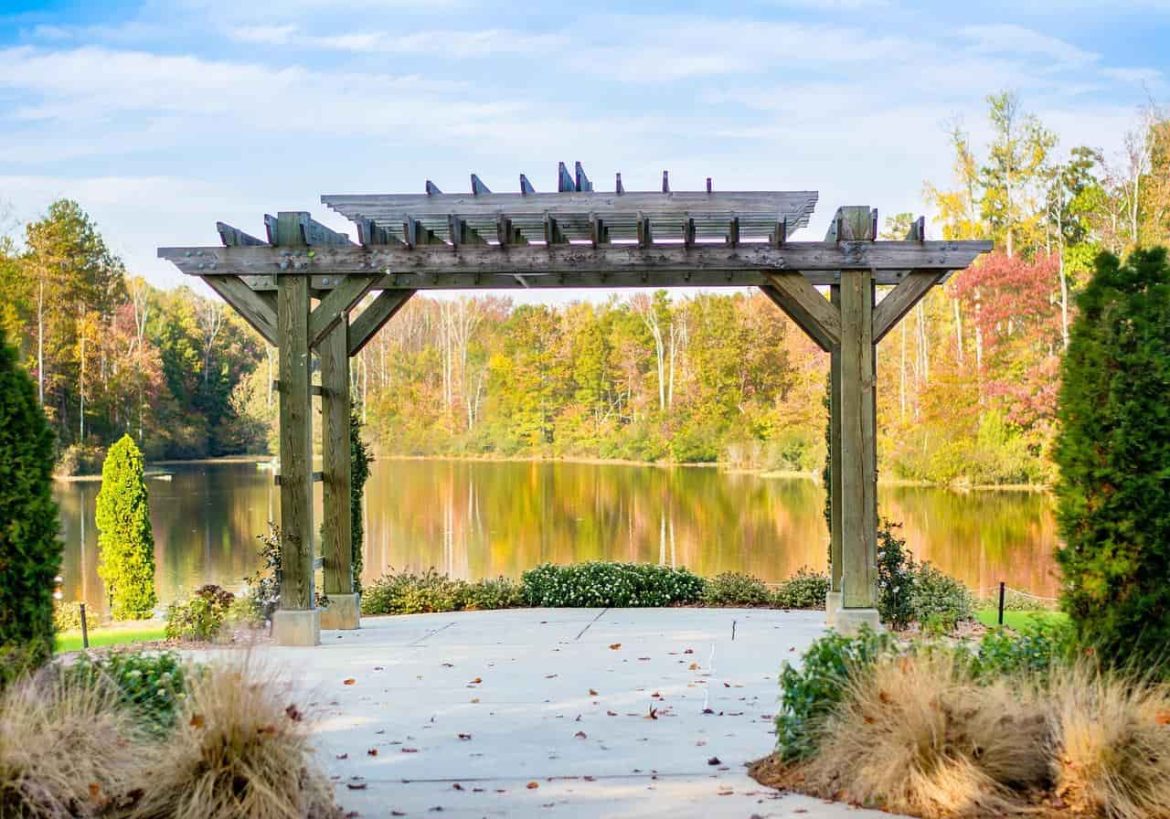 Une structure de pergola en bois robuste installée au bord d'un lac paisible, idéale pour l'ajout d'une moustiquaire pergola afin de profiter de la vue sans insectes