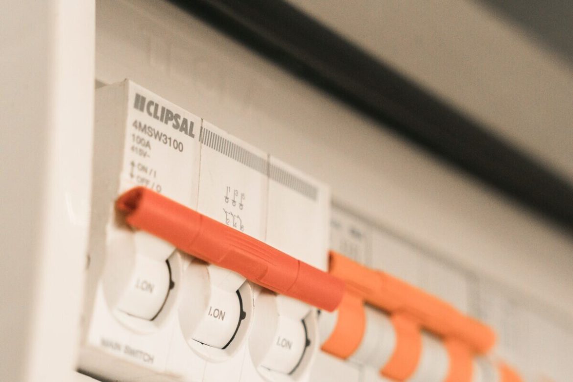 Gros plan sur un interrupteur principal de marque Clipsal avec une poignée rouge, situé dans un tableau électrique domestique, probablement suite à une panne de courant.