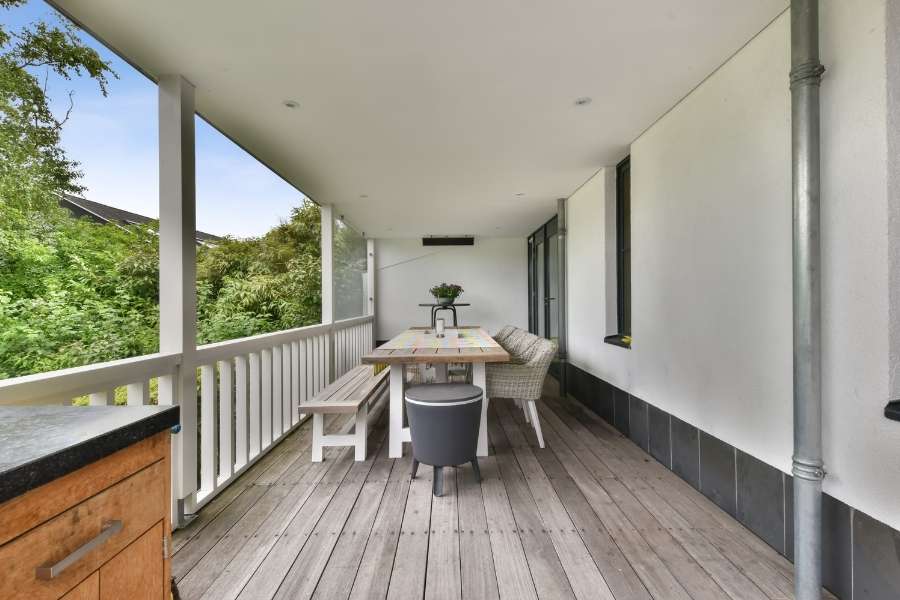 Une terrasse couverte en bois avec une table et des bancs pour un coin repas ombragé.