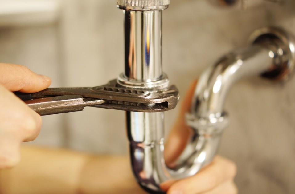Serrage d'un raccord de siphon chromé avec une pince multiprise selon les normes plomberie sanitaire en vigueur